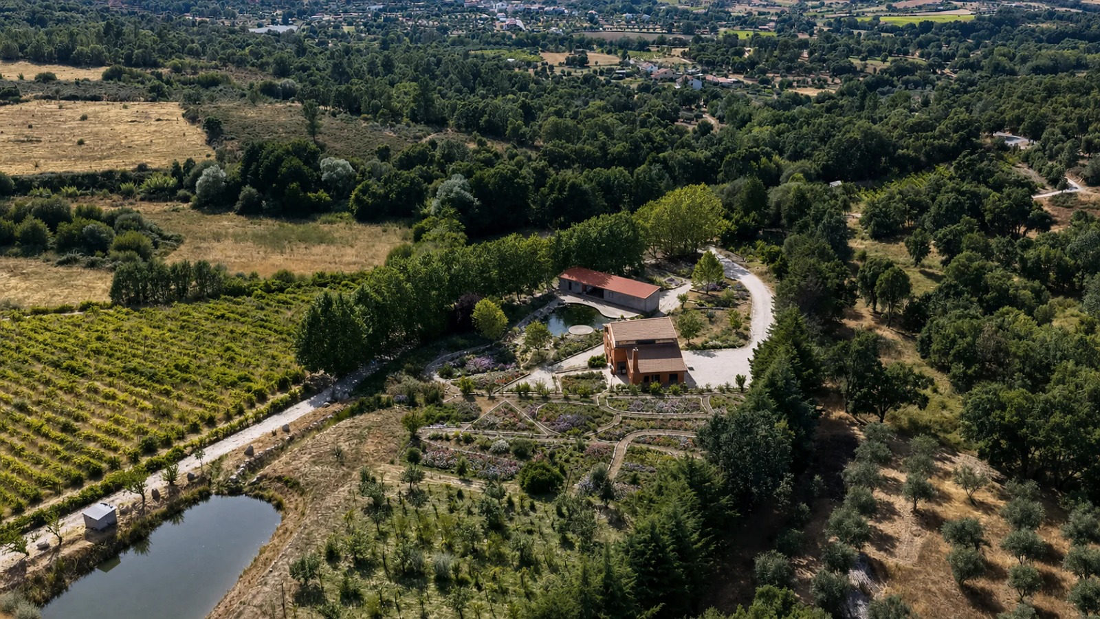Aerial view of the estate — terracotta roofs, geometric gardens, vineyard and forest in Aldeia Nova do Cabo, Fundão